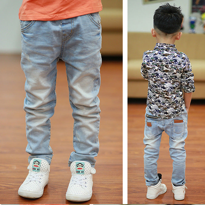 Blue jeans with zippers and buttons, standing on a wooden floor.