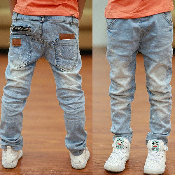 Blue jeans with zippers and buttons, standing on a wooden floor.