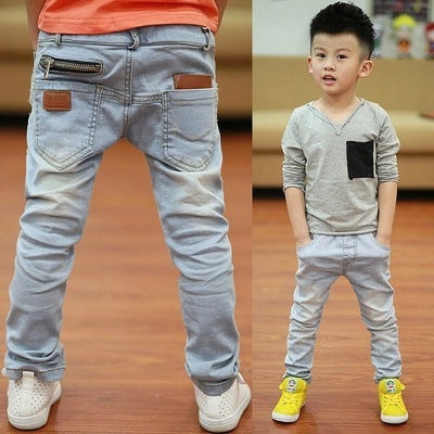 Blue jeans with zippers and buttons, standing on a wooden floor.